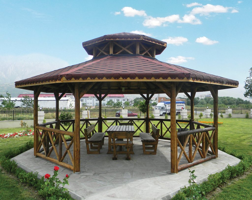 Park alanında altıgen ahşap kamelya, masa ve oturma grubuyla